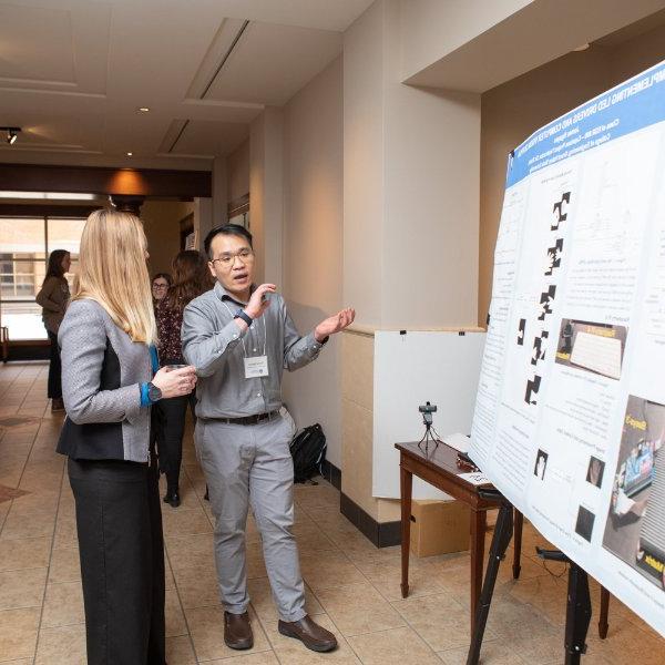 A graduate student presents their poster at the Graduate Showcase.